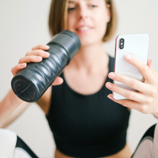 ondernemer die sport en kijkt op mobiel en daarbij gezondheid en ondernemen combineert