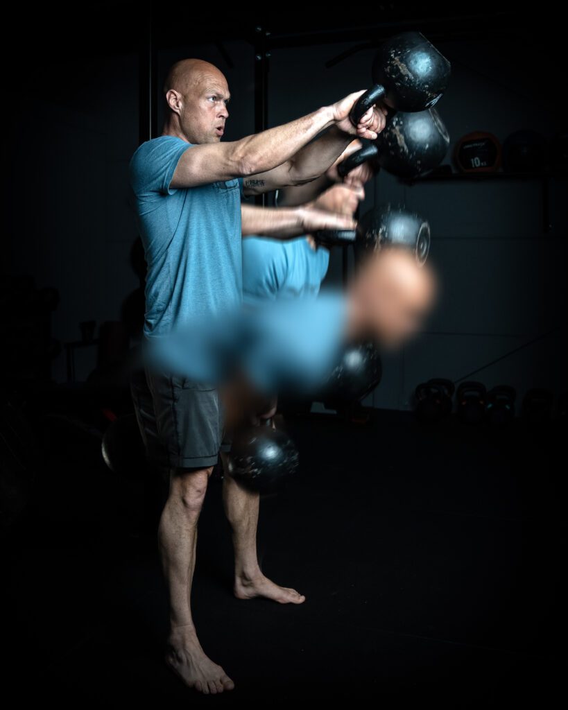 Trainer Ronald voert een kettlebell swing uit.